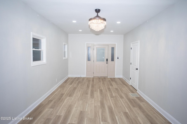 hall with a chandelier and light hardwood / wood-style floors