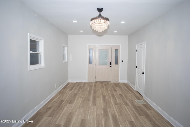 hallway with a chandelier and light hardwood / wood-style floors