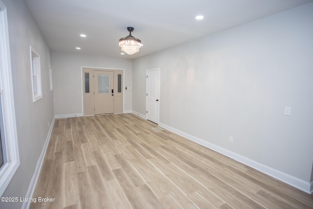 empty room with a chandelier and light hardwood / wood-style flooring