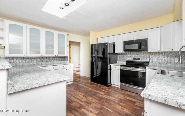 kitchen featuring backsplash, a skylight, sink, black appliances, and white cabinetry