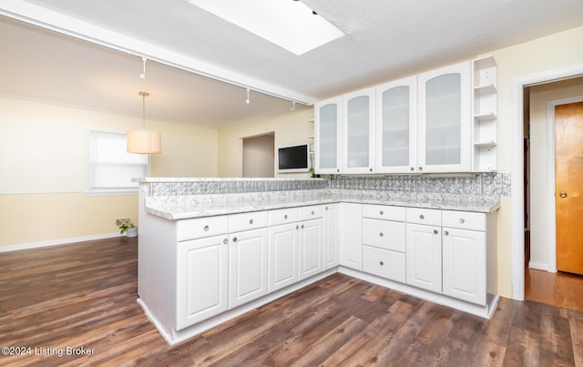 kitchen featuring kitchen peninsula, light stone countertops, decorative light fixtures, dark hardwood / wood-style flooring, and white cabinetry