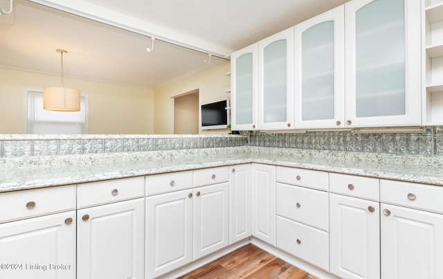 kitchen featuring white cabinetry, dark wood-type flooring, tasteful backsplash, light stone counters, and decorative light fixtures