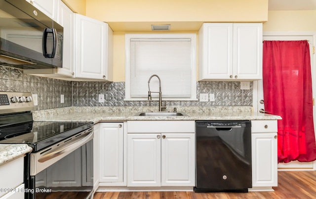 kitchen with black appliances, light stone counters, white cabinets, and sink