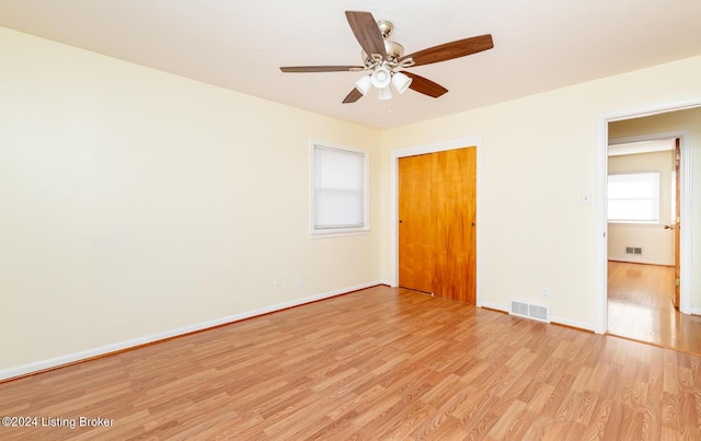 unfurnished bedroom with ceiling fan, a closet, and light wood-type flooring