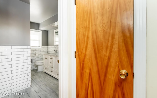 bathroom featuring vanity, tile walls, and toilet