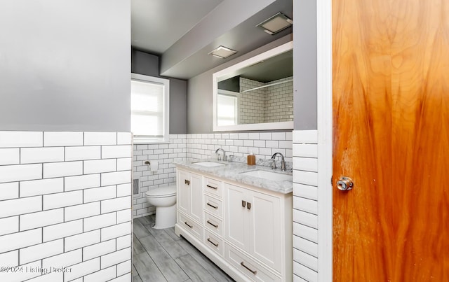 bathroom with vanity, tile walls, and toilet