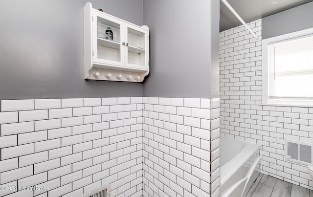 bathroom featuring tiled shower / bath and tile walls