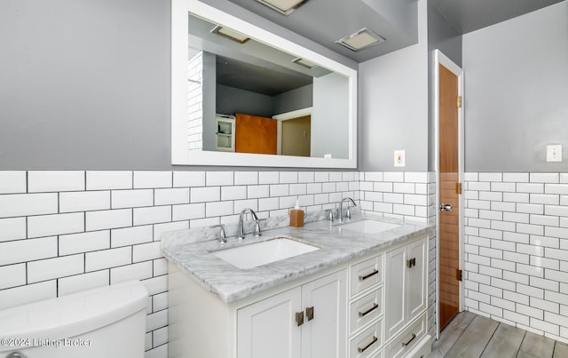 bathroom featuring vanity, tile walls, and toilet