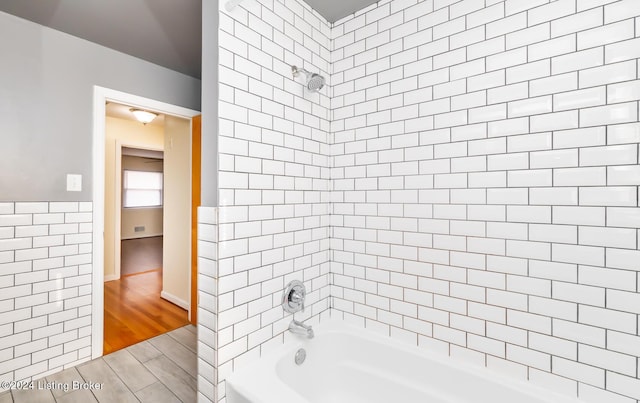 bathroom featuring tile walls and tiled shower / bath combo