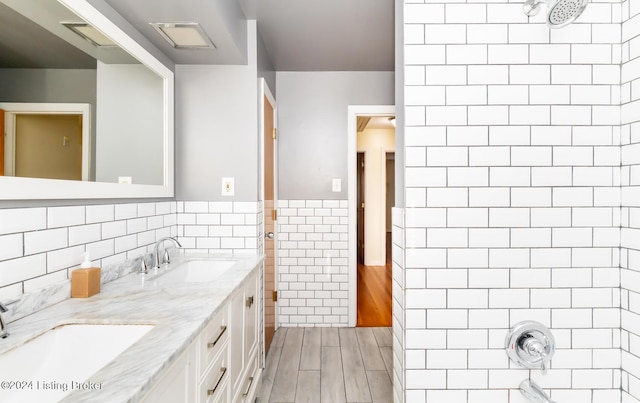 bathroom with shower / bathing tub combination, vanity, and tile walls