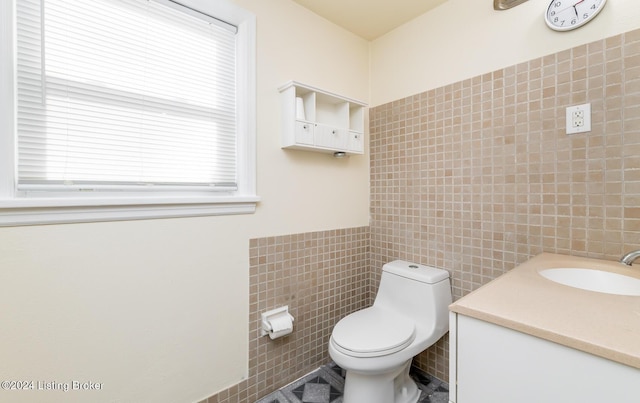 bathroom with vanity, toilet, and tile walls