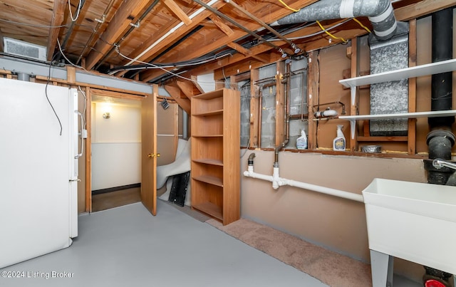 basement featuring sink and white refrigerator