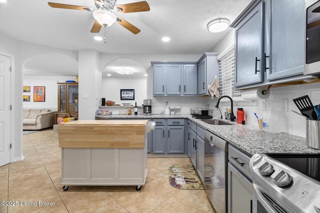 kitchen with sink, ceiling fan, light tile patterned floors, appliances with stainless steel finishes, and tasteful backsplash