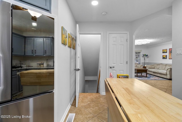 kitchen featuring stainless steel fridge, light tile patterned floors, and backsplash