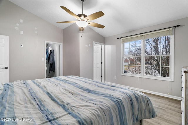 bedroom with vaulted ceiling, ceiling fan, a spacious closet, light hardwood / wood-style floors, and a closet