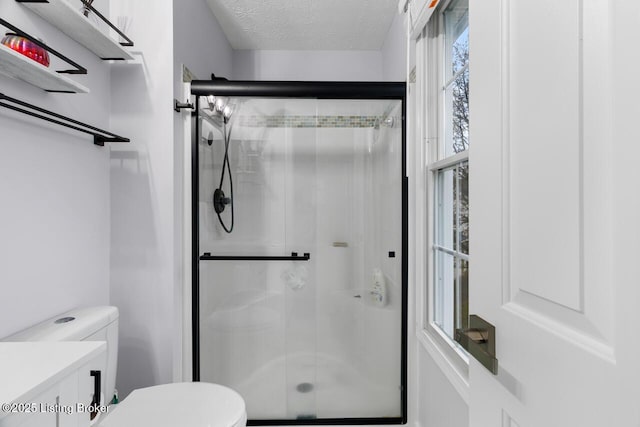 bathroom with a shower with door, vanity, a textured ceiling, and toilet