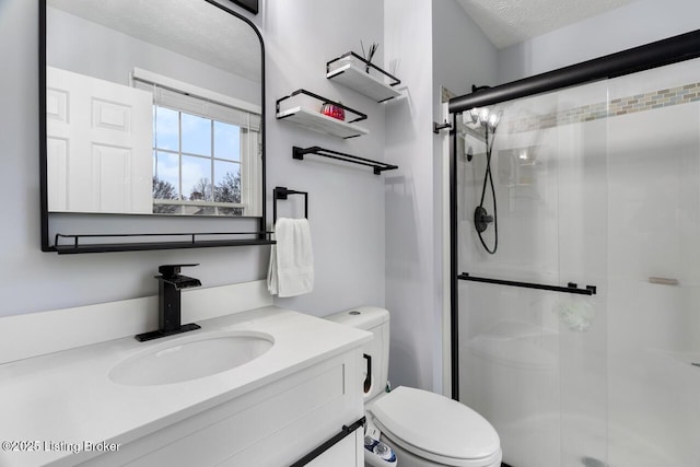 bathroom featuring vanity, a textured ceiling, toilet, and a shower with door