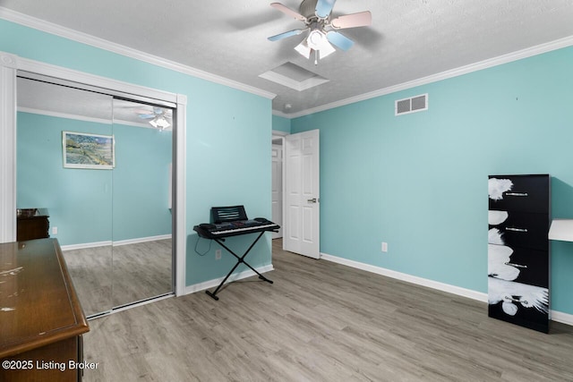 interior space with a textured ceiling, ceiling fan, crown molding, hardwood / wood-style floors, and a closet