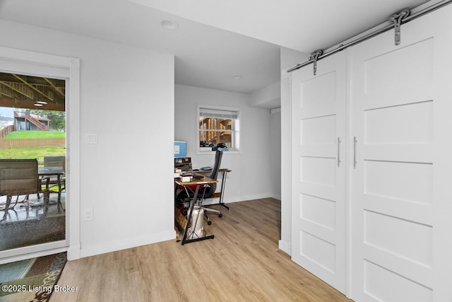 office with a barn door, light hardwood / wood-style floors, and a healthy amount of sunlight