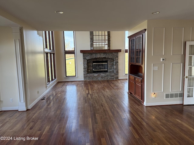 unfurnished living room featuring dark hardwood / wood-style floors and a stone fireplace