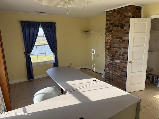 tiled home office featuring ceiling fan and a water view