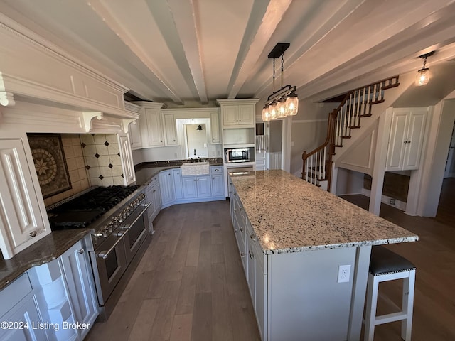 kitchen featuring beam ceiling, a center island, white cabinets, and hanging light fixtures