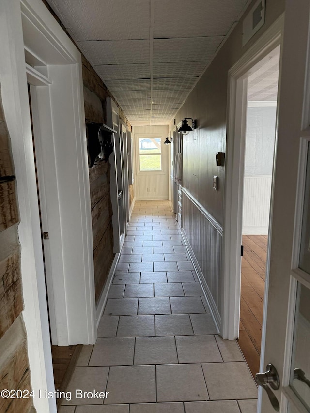 corridor with wooden walls and light tile patterned floors