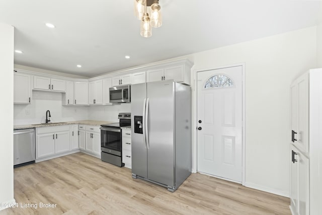 kitchen featuring sink, light stone countertops, light hardwood / wood-style floors, white cabinetry, and stainless steel appliances