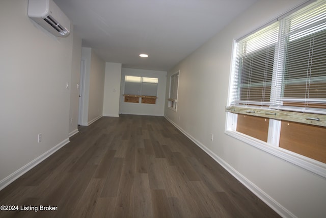 hallway with a wall unit AC and dark hardwood / wood-style flooring