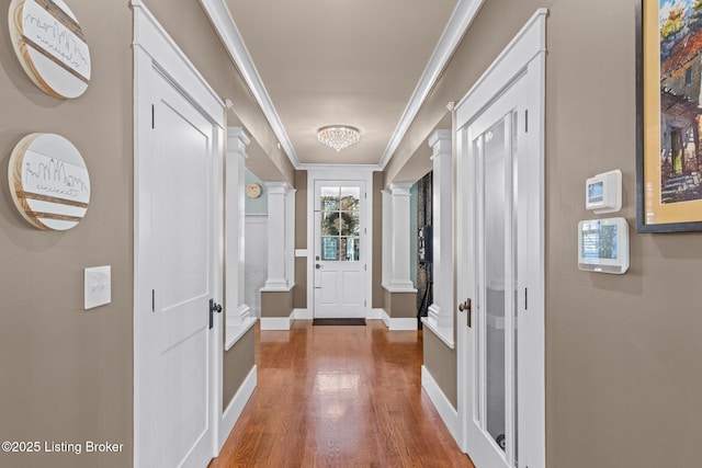 hall with crown molding, hardwood / wood-style floors, and decorative columns