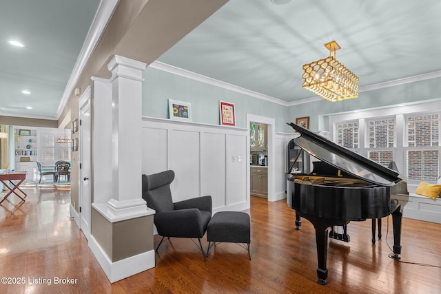 living area with decorative columns, plenty of natural light, hardwood / wood-style floors, and an inviting chandelier