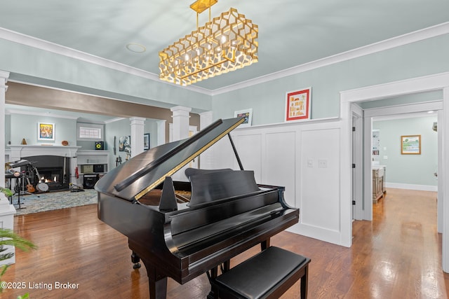 misc room featuring crown molding, wood-type flooring, and decorative columns