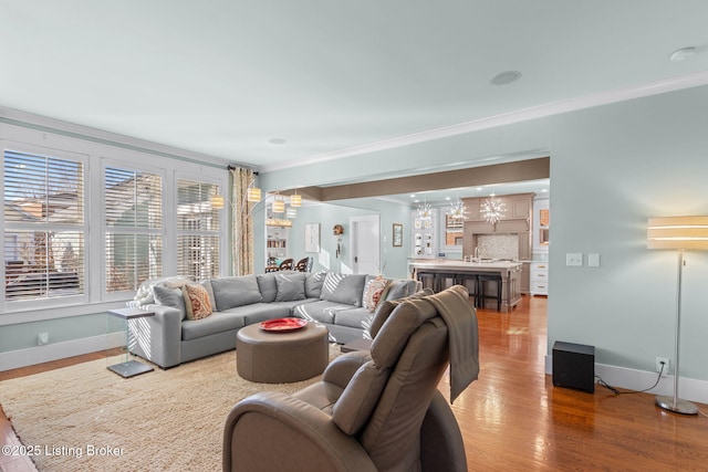 living room with a notable chandelier, ornamental molding, hardwood / wood-style floors, and sink