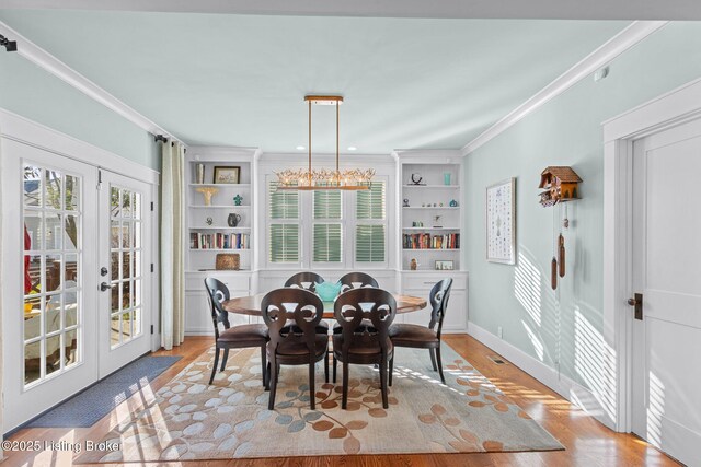 dining room featuring crown molding, a healthy amount of sunlight, french doors, and light hardwood / wood-style flooring