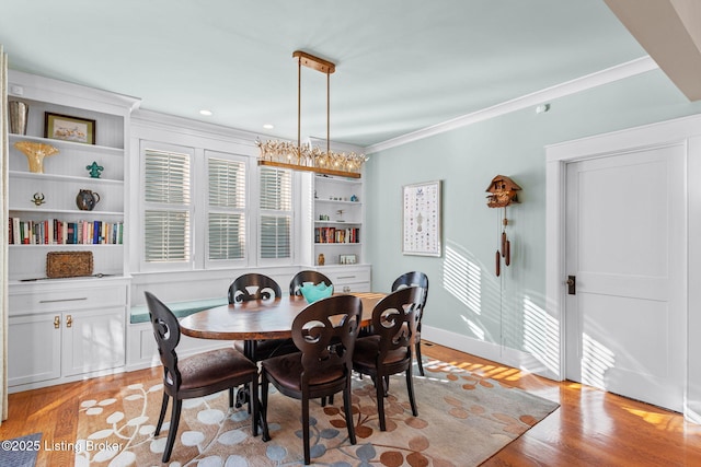 dining room with crown molding, light hardwood / wood-style flooring, and built in shelves