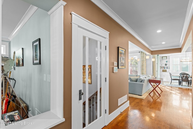 corridor with a notable chandelier, ornamental molding, and hardwood / wood-style floors