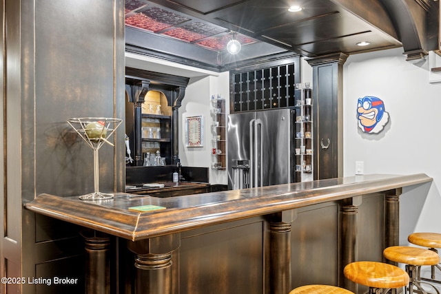 bar featuring stainless steel refrigerator with ice dispenser