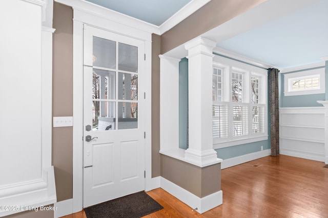 interior space featuring crown molding, hardwood / wood-style floors, and ornate columns