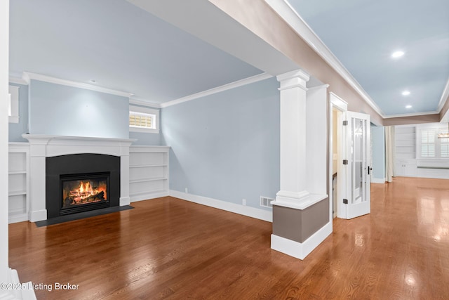 unfurnished living room with built in shelves, ornamental molding, hardwood / wood-style floors, and ornate columns