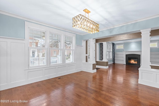 unfurnished living room featuring crown molding, dark wood-type flooring, decorative columns, and built in shelves