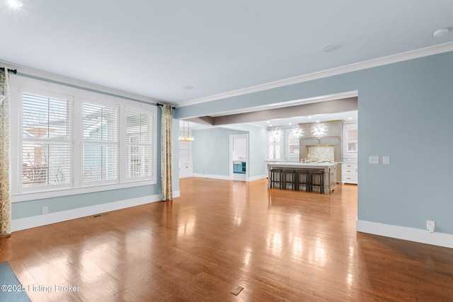 unfurnished living room featuring ornamental molding, a chandelier, and hardwood / wood-style floors