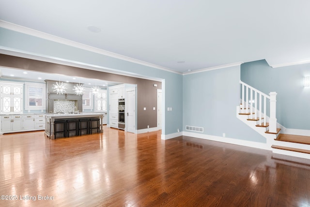 unfurnished living room featuring ornamental molding and hardwood / wood-style floors