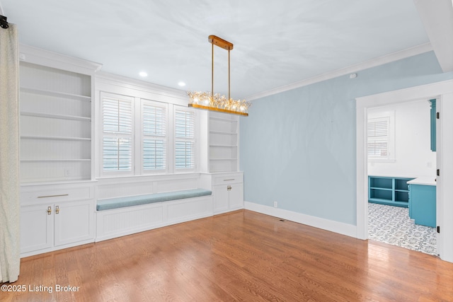 unfurnished dining area featuring crown molding, built in shelves, and light wood-type flooring