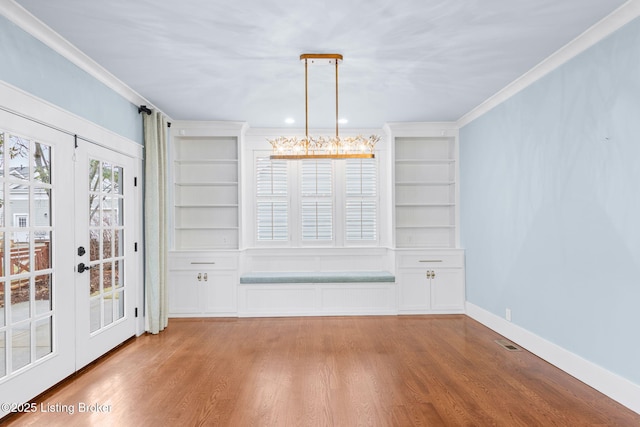 unfurnished dining area with crown molding, built in features, light hardwood / wood-style floors, and french doors