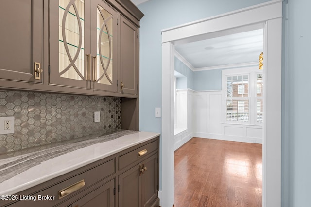 bar featuring crown molding, light hardwood / wood-style floors, tasteful backsplash, and gray cabinetry