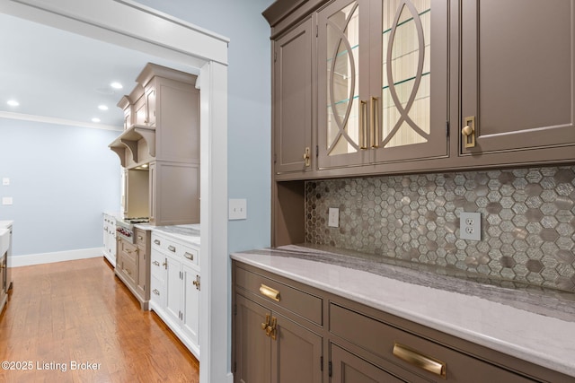 kitchen with backsplash, light hardwood / wood-style flooring, ornamental molding, and gray cabinets