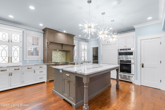 kitchen with a breakfast bar, double oven, decorative light fixtures, an inviting chandelier, and a spacious island