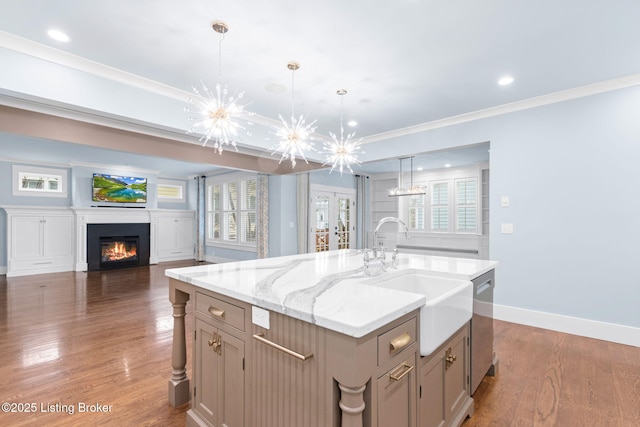 kitchen with decorative light fixtures, an island with sink, sink, stainless steel dishwasher, and an inviting chandelier