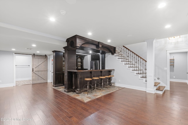 bar with hardwood / wood-style flooring, a barn door, high end fridge, and ornate columns