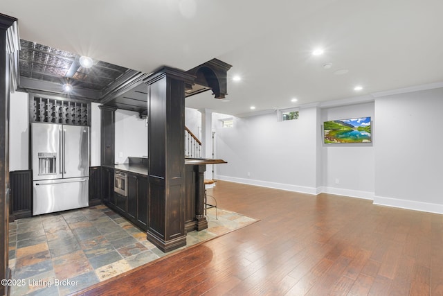 kitchen featuring a breakfast bar, ornate columns, high quality fridge, dark hardwood / wood-style floors, and kitchen peninsula